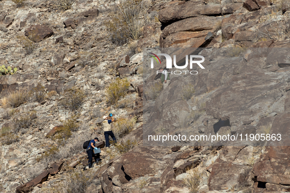 A rescue team climbs a hill to recover the body of the immigration officer who loses his life during an attack with rocks thrown by migrants...