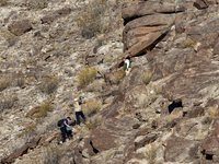 A rescue team climbs a hill to recover the body of the immigration officer who loses his life during an attack with rocks thrown by migrants...