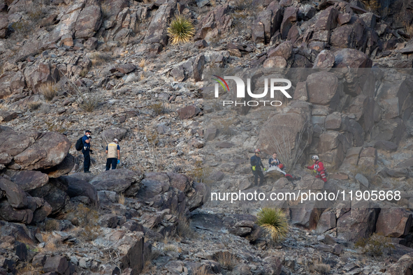 A rescue team climbs a hill to recover the body of the immigration officer who loses his life during an attack with rocks thrown by migrants...