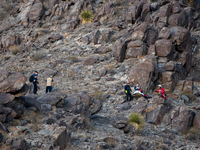 A rescue team climbs a hill to recover the body of the immigration officer who loses his life during an attack with rocks thrown by migrants...