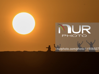 People ride on a camel along the Sealine Sand Dunes against the backdrop of the last sunset of the year 2024 in Sealine, Qatar, on December...