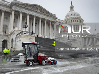 A crew clears snow from the plaza and steps at the United States Capitol on the anniversary of the January 6, 2021, insurrection in Washingt...