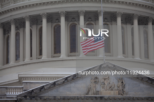 A flag flies at half-staff in honor of President Jimmy Carter, who passed away Dewcember 29, as snow falls on the Capitol on the anniversary...