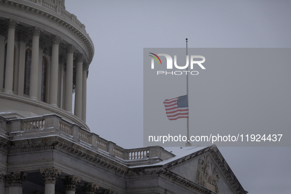 A flag flies at half-staff in honor of President Jimmy Carter, who passed away Dewcember 29, as snow falls on the Capitol on the anniversary...