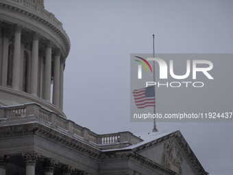 A flag flies at half-staff in honor of President Jimmy Carter, who passed away Dewcember 29, as snow falls on the Capitol on the anniversary...