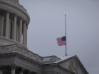 A flag flies at half-staff in honor of President Jimmy Carter, who passed away Dewcember 29, as snow falls on the Capitol on the anniversary...