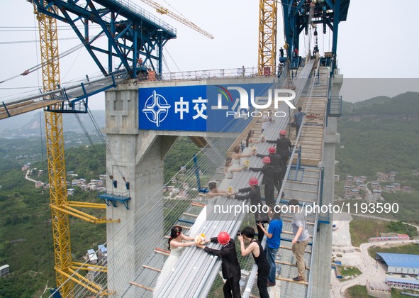 Young couples have their wedding photos taken up on a suspension bridge over the Yangtze River in southwest China's Chongqing Municipality,...