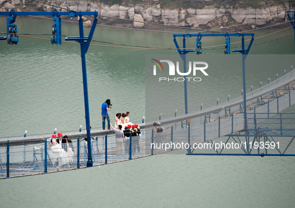 Young couples have their wedding photos taken on a suspension bridge over the Yangtze River in southwest China's Chongqing Municipality, May...