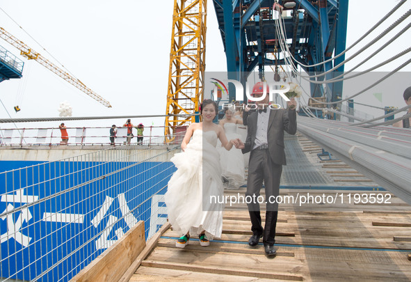 Young couples walk up to have their wedding photos taken on a suspension bridge over the Yangtze River in southwest China's Chongqing Munici...