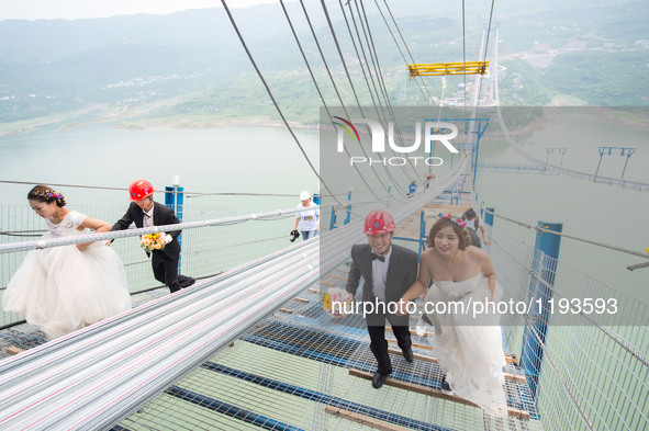 Young couples walk up to have their wedding photos taken on a suspension bridge over the Yangtze River in southwest China's Chongqing Munici...