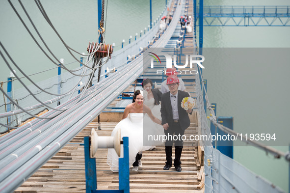 Young couples walk up to have their wedding photos taken on a suspension bridge over the Yangtze River in southwest China's Chongqing Munici...