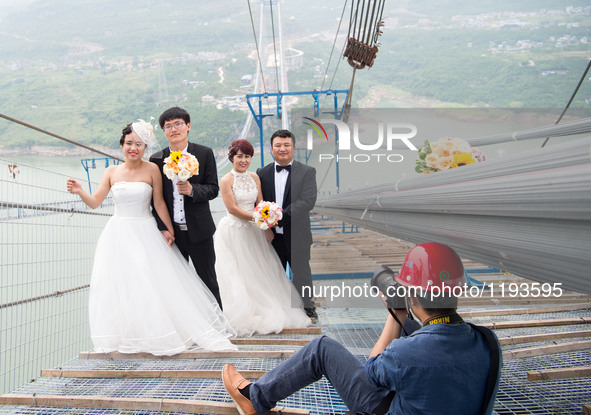 Young couples have their wedding photos taken on a suspension bridge over the Yangtze River in southwest China's Chongqing Municipality, May...