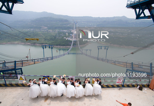 Young couples have their wedding photos taken on a suspension bridge over the Yangtze River in southwest China's Chongqing Municipality, May...