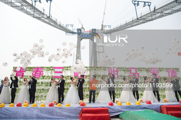 Young couples have their wedding photos taken up on a suspension bridge over the Yangtze River in southwest China's Chongqing Municipality,...