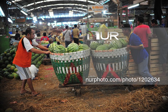 Indonesian workers transport baskets of watermelons at a fresh food and vegetable market in Jakarta, Indonesia, May 10, 2016.