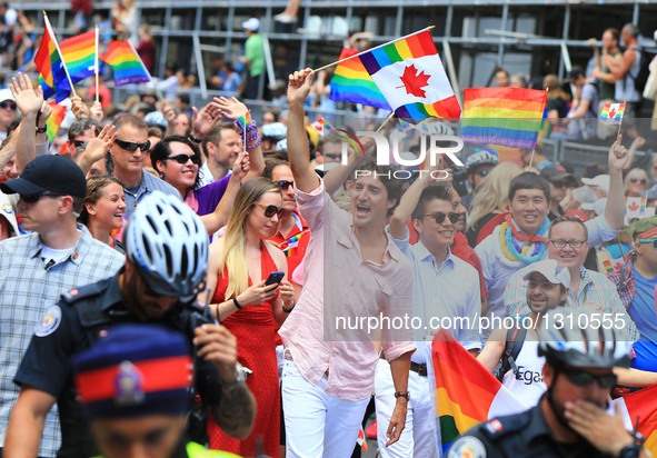 Canadian Prime Minister Justin Trudeau (C) waves a flag as he takes part in the 2016 Toronto Pride Parade in Toronto, Canada, July 3, 2016.