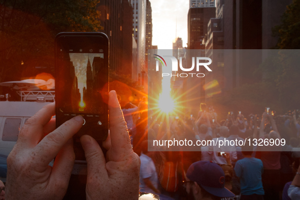 A man takes photo of Manhattanhenge with his iPhone in Manhattan, New York, the United States, July 11, 2016. The Manhattanhenge refers to t...