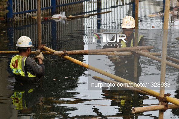 Workers set up a temporary trestle at a neighborhood in Wuhan, capital of central China's Hubei Province, July 12, 2016. In order to prepare...