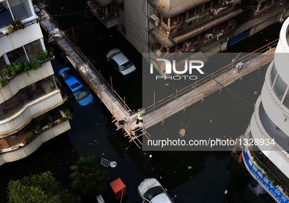 Workers set up a temporary trestle at a neighborhood in Wuhan, capital of central China's Hubei Province, July 12, 2016. In order to prepare...