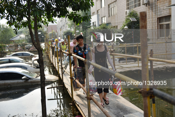 Local residents walk on a temporary trestle at a neighborhood in Wuhan, capital of central China's Hubei Province, July 12, 2016. In order t...