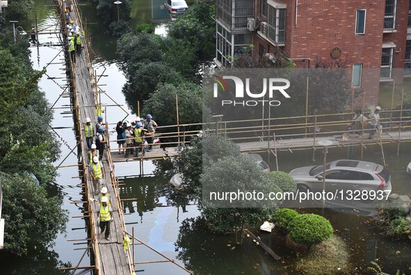 Workers set up a temporary trestle at a neighborhood in Wuhan, capital of central China's Hubei Province, July 12, 2016. In order to prepare...