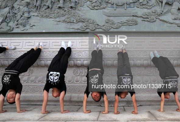 Students of a Peking Opera troupe practise handstand at Kaiyuan Temple Square in Xingtai, north China's Hebei Province, July 17, 2016. Many...