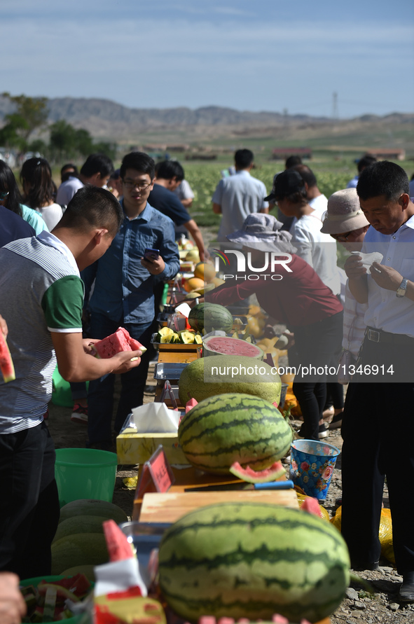 Customers and retailers taste watermelons in Xingren Town of Zhongwei City, northwest China's Ningxia Hui Autonomous Region, July 23, 2016....