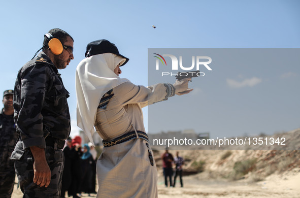 A Palestinian girl aims a pistol as she prepares to fire at a target during a training session for the families of Hamas officials, organize...