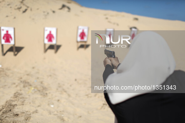 A Palestinian girl aims a pistol as she prepares to fire at a target during a training session for the families of Hamas officials, organize...