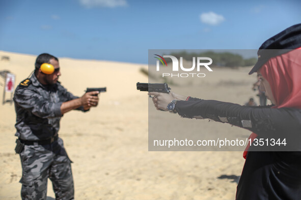 A Palestinian girl aims a pistol as she prepares to fire at a target during a training session for the families of Hamas officials, organize...