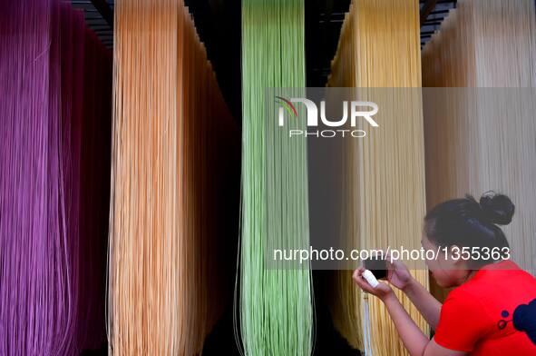 Luo Xiaoqing takes photos of colored vegetable noodles in Zhongcunba Village of Xuan'en County in Enshi, central China's Hubei Province, Jul...