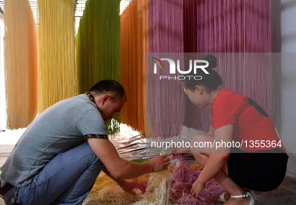 Xiao Hui (L) and Luo Xiaoqing arrange colored vegetable noodles in Zhongcunba Village of Xuan'en County in Enshi, central China's Hubei Prov...