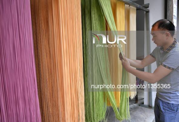 Xiao Hui checks the quality of colored vegetable noodles in Zhongcunba Village of Xuan'en County in Enshi, central China's Hubei Province, J...