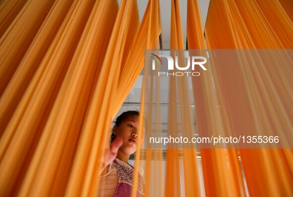 Luo Xiaoqing dries carrot noodles in Zhongcunba Village of Xuan'en County in Enshi, central China's Hubei Province, July 26, 2016. The post-...