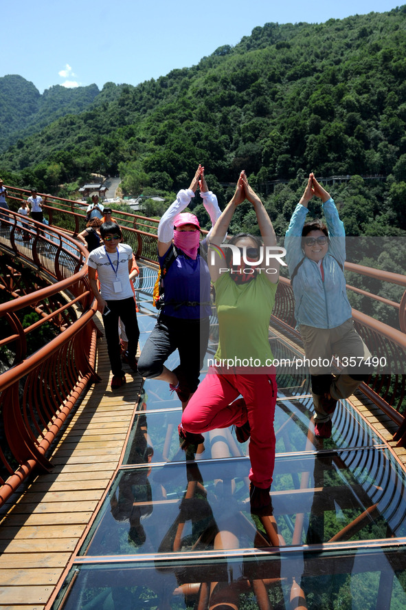 Tourists pose for a photo on a 69-meter-long glass pathway built along the face of a cliff in Shaohuashan national forest park in Weinan Cit...