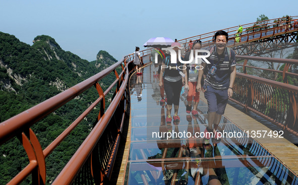 Tourists walk on a 69-meter-long glass pathway built along the face of a cliff in Shaohuashan national forest park in Weinan City, northwest...