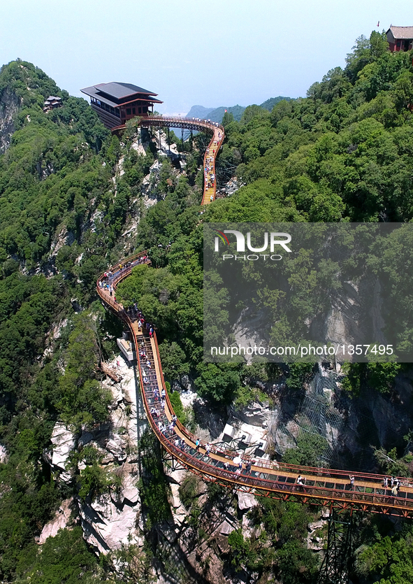 Tourists walk on a 69-meter-long glass pathway built along the face of a cliff in Shaohuashan national forest park in Weinan City, northwest...