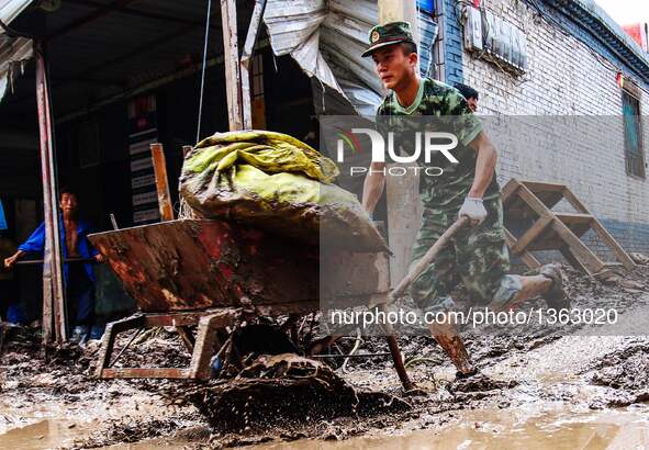 A soldier removes slush from streets in Jingxing County, north China's Hebei Province, July 29, 2016. A total of 2,400 soldiers have been di...