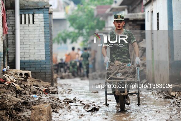 A soldier removes slush from streets in Jingxing County, north China's Hebei Province, July 29, 2016. A total of 2,400 soldiers have been di...