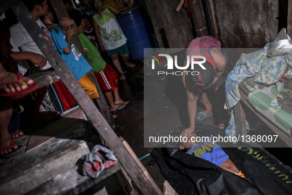 (EDITORS NOTE: Image depicts graphic content.) A resident covers the face of a suspected drug pusher who was shot dead following a police op...