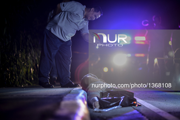 (EDITORS NOTE: Image depicts graphic content.) A member of the police's homicide division inspects the corpse of a suspected drug addict and...