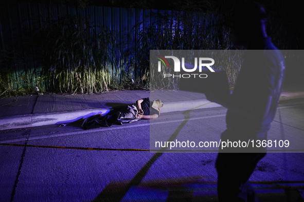 (EDITORS NOTE: Image depicts graphic content.) A police investigator inspects the corpse of a suspected drug addict and victim of a vigilant...