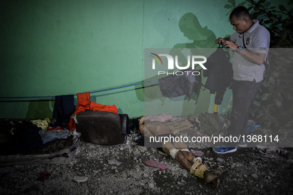 (EDITORS NOTE: Image depicts graphic content.) A member of the police's homicide division takes pictures of the corpse of a suspected house...