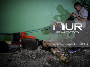 (EDITORS NOTE: Image depicts graphic content.) A member of the police's homicide division takes pictures of the corpse of a suspected house...