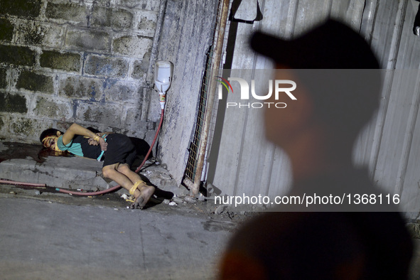 (EDITORS NOTE: Image depicts graphic content.) A police officer stands next to the corpse of a suspected drug pusher and victim of a vigilan...