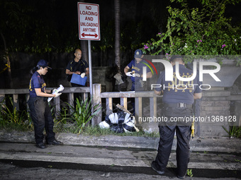 (EDITORS NOTE: Image depicts graphic content.) Police investigators inspect the corpse of a suspected drug pusher and victim of a vigilante-...