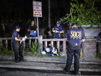 (EDITORS NOTE: Image depicts graphic content.) Police investigators inspect the corpse of a suspected drug pusher and victim of a vigilante-...