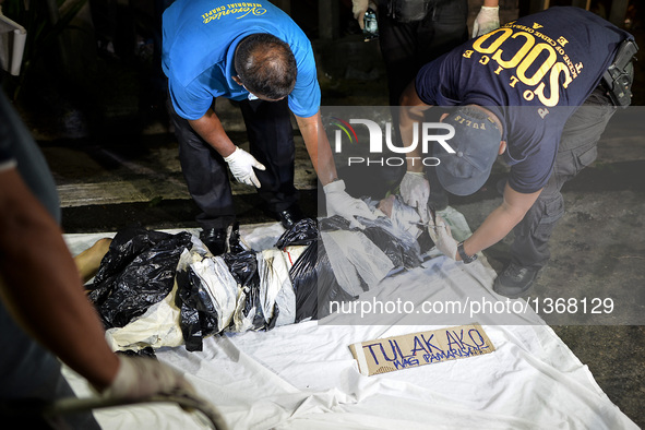 (EDITORS NOTE: Image depicts graphic content.) Police investigators inspect the corpse of a suspected drug pusher and victim of a vigilante-...