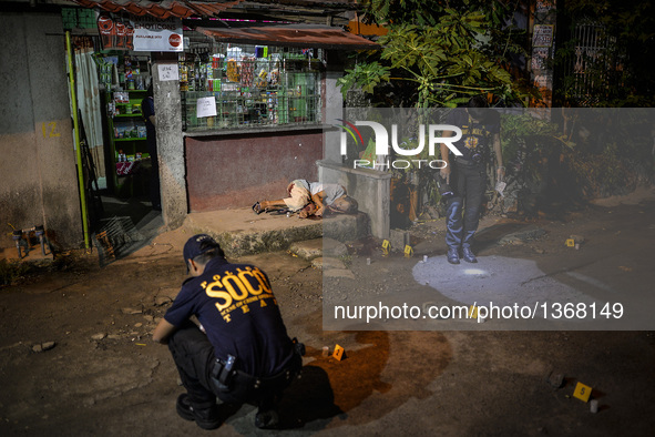 (EDITORS NOTE: Image depicts graphic content.) Police investigators inspect empty bullet shells scattered on the ground as the corpse of a s...