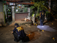 (EDITORS NOTE: Image depicts graphic content.) Police investigators inspect empty bullet shells scattered on the ground as the corpse of a s...